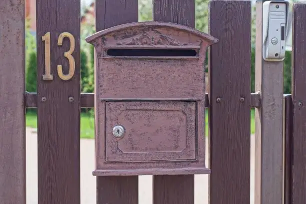 Photo of one brown metal mailbox on a wooden fence from boards