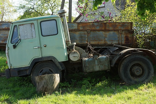 one old big lorry with a green cab is standing in the grass outdoors on the street