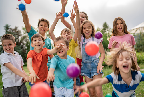 Group of children are plays and throw colorful balls