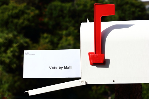 Vintage red mail box at home garden surrounded by green tree