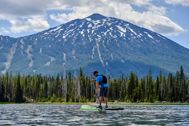 joven paddle tablas a través del lago - mountain mountain peak oregon on top of fotografías e imágenes de stock