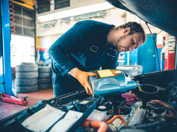 Auto Mechanic working on car Young Caucasian worker at the auto mechanic shop. Location portrait at the place of work. car portrait men expertise stock pictures, royalty-free photos & images