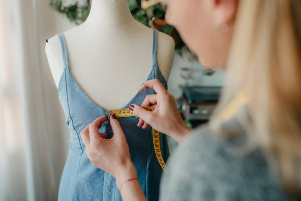 マネキンを測定する若い女性のファッションデザイナー、居心地の良い家や仕立屋でダミーで作業するテープを保持している縫い目、洋裁や縫製のコンセプト、 - owner embroidery small business indoors ストックフォトと画像