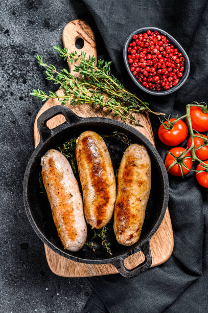 istock Pork sausages in a cast-iron pan. Black background. Top view 1227019179