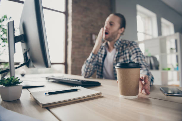 Blurry focus photo of handsome business guy look computer monitor on table finish deadline report in time need some coffee, take fresh hot mug yawning wear casual shirt sit office indoors blurry focus foto de guapo hombre de negocios mira monitor de computadora en la mesa fin de fecha límite informe en el tiempo necesita un poco de café tomar taza caliente fresca bostezando de ropa camisa casual sentarse oficina en interiores