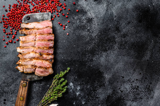 istock Sliced marble pork cutlet steak with spices and herbs. Black background. Top view. Copy space 1227022595