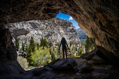 A woman doing yoga from a cave with a beautiful view.