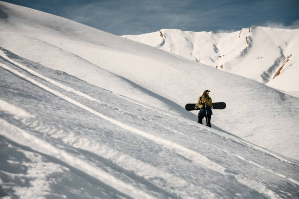 мужской фрирайдер со сноубордом позирует на склоне горы - climbing individual sports sports and fitness snowboard стоковые фото и изображения