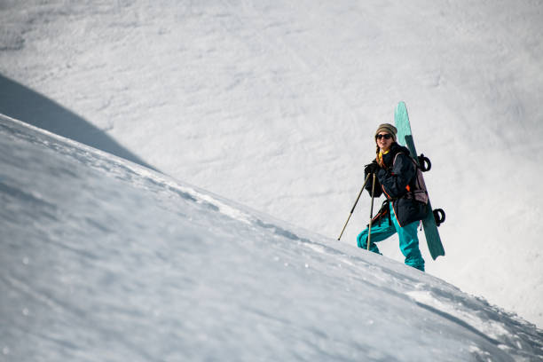 istock Female hiker goes up the mountain with snowboard 1227026837