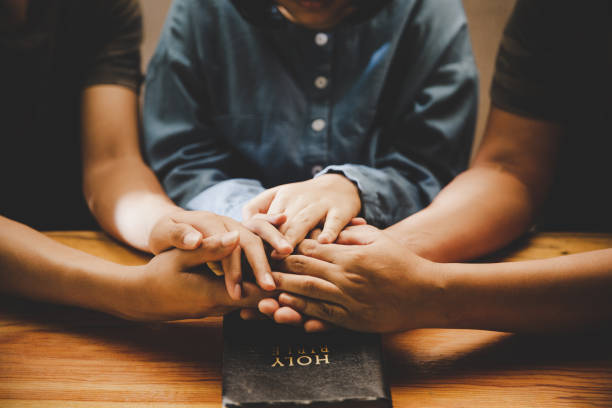 rodzina modlić się razem modląc się z rodzicem w domu - praying bible church human hand zdjęcia i obrazy z banku zdjęć