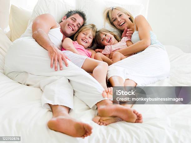 Family Of Four Dressed In White And Cuddling In Bed Stock Photo - Download Image Now