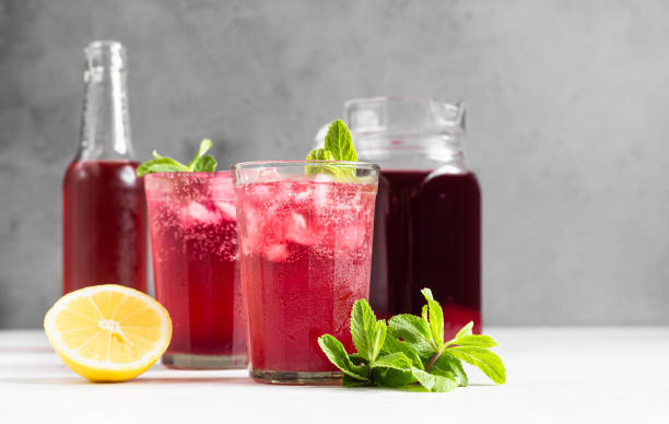 limonada rosa brillante con limón y menta sobre fondo de hormigón gris claro. bebida de refresco de verano. - raspberry soda fotografías e imágenes de stock