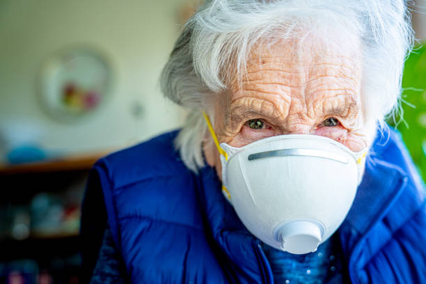 close-up shot of elderly senior caucasian woman wearing an n95 protective face mask to prevent the spread of covid sars ncov 19 coronavirus swine flu h7n9 influenza illness during cold and flu season - flu virus cold and flu swine flu epidemic imagens e fotografias de stock