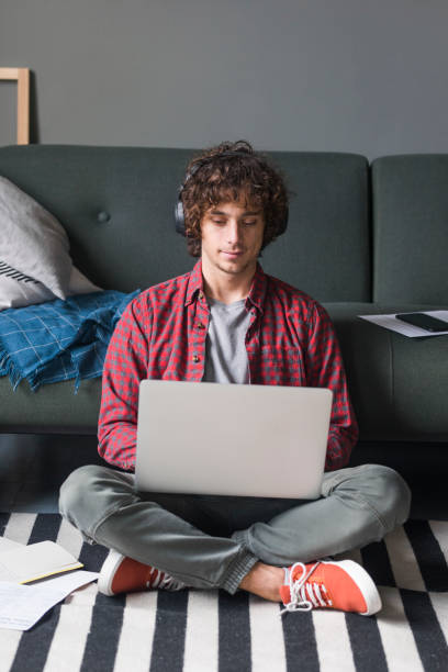 istock Learning and Studying from Home: a College Student With Headphones Attending an Online Course by Using his Laptop Computer 1227031498