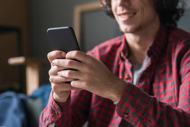 istock Smiling Young Man in a Casual Red Checked Shirt Using his Mobile Phone at Home 1227031531