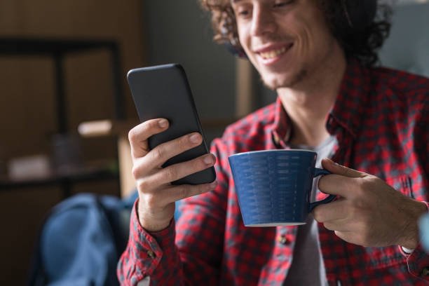 istock Smiling Young Man in a Casual Red Checked Shirt Using his Mobile Phone at Home 1227031537