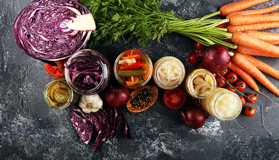 Preserves vegetables in glass jars. Pickled Cucumber, carrot, fermented cabbage and onions on rustic table