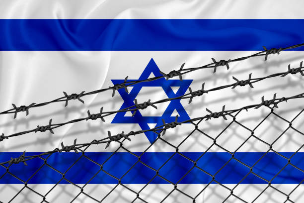 istock Developing Israel Flag, mesh fence and barbed wire. Concept of isolation of emigrants. With place for your text. 1227032810