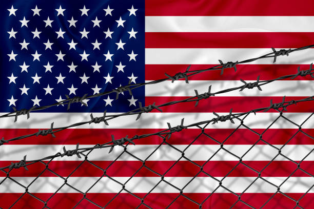 istock Developing US Flag, mesh fence and barbed wire. Concept of isolation of emigrants. With place for your text.; 1227033085