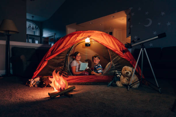 istock Girl and Boy Reading while Camping Indoors 1227035089