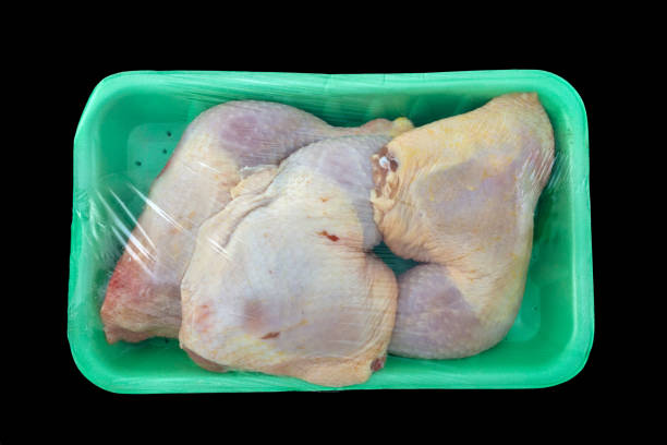 Raw chicken legs in green packaged on isolated black background