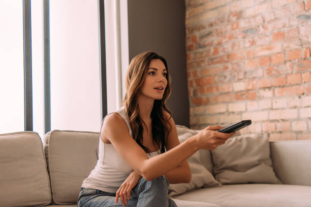 istock attractive woman holding remote controller and watching tv during self isolation 1227040128