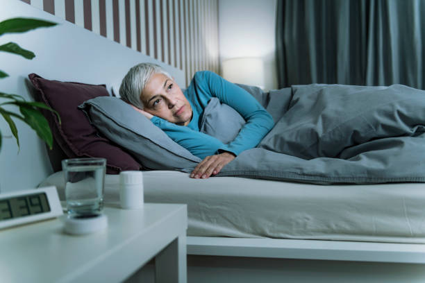 insomnia - sleep disorder. worried senior woman suffering from insomnia, lying in bed, staying awake late at night - old senior adult women tired imagens e fotografias de stock