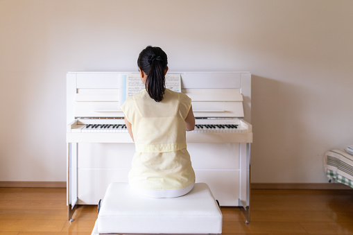 rear view of woman playing the piano at home