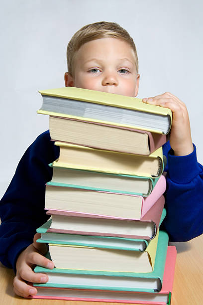 istock young boy looking out from top of books 122704773
