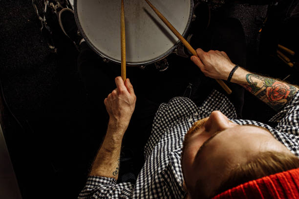 young caucasian drummer rehearsing on drums before rock concert. professional artiste man recording music on drum set in dark studio