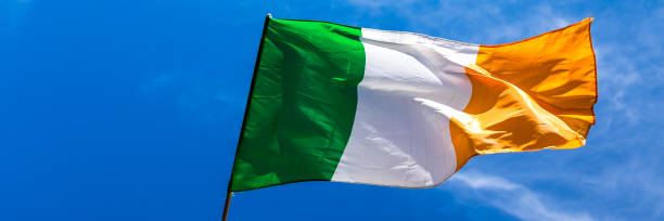istock Irish flag fluttering in a brisk breeze against a bright blue sky. Web banner. 1227052296
