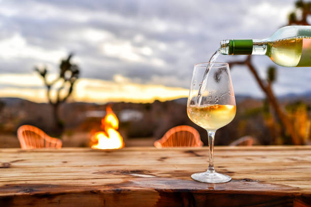 pouring wine with desert sunset and fire pit backdrop - wine pouring wineglass white wine fotografías e imágenes de stock