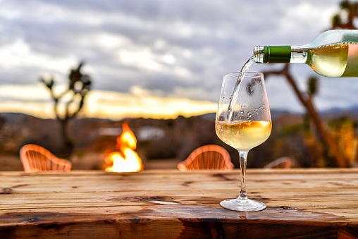 Pouring Wine with Desert Sunset and Fire Pit Backdrop