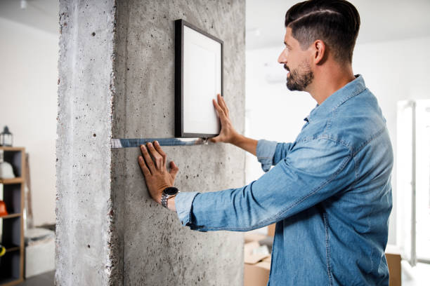 istock Bearded man fixing photo frame on wall with ruler 1227054355