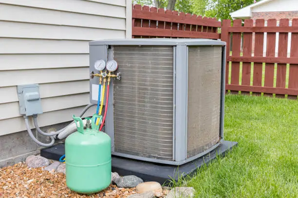 Photo of Dirty air conditioning condenser coils full of dirt and debris. Freon charging tools. Concept of home air conditioner repair, service, cleaning and maintenance