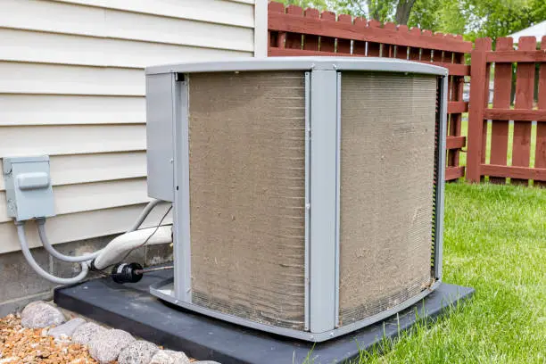 Photo of Dirty air conditioning unit. Condenser coil full of dirt and grass debris. Concept of home air conditioner repair, service, cleaning and maintenance