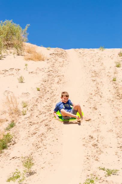 istock Boy Sliding Down Sand Dune at Little Sahara Recreation Area 1227061493