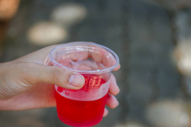 istock Female hand holding water glass with red liquid drink 1227063247