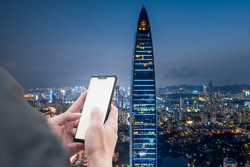 Hands holding cell phones in Shenzhen high-rise building