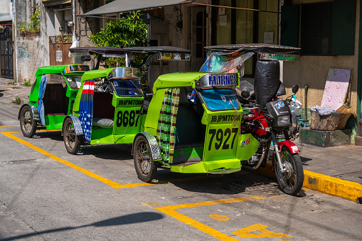 Tricycles waiting at a street for people wanting delivery services. These vehicles are a form of basic local transportation common in the Philippines