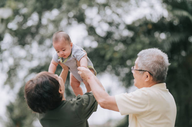 アジアの中国の先輩夫婦が、家の前庭で孫と遊んでいる - senior adult women adult tan ストックフォトと画像