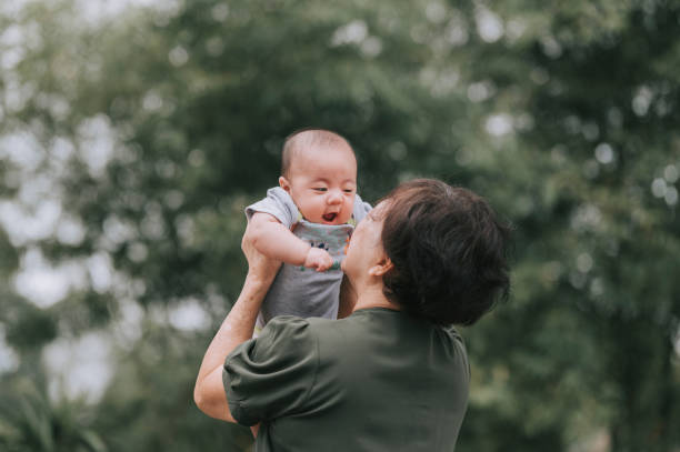 una donna asiatica cinese senior che gioca con suo nipote nel cortile anteriore della loro casa - baby grandparent newborn grandmother foto e immagini stock