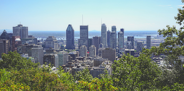 Montreal view from Mount Royal in summer day. Postcard like view of central down town area of Montreal from Mount Royal in sunny day. Silhouette of business in front of blue horizon.