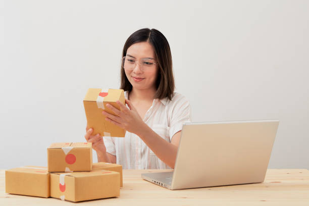 istock Happy asian woman work from home packaging  and writing order with cardboard box 1227072967