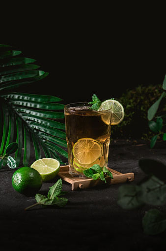 Cold black tea with fresh lime on dark background