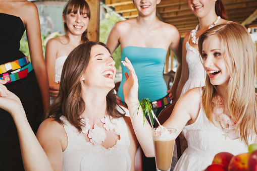 Having Fun at a Teenage Girl's Birthday Party. Girls joking around together celebrating a teenage girls-only birthday party, Playing with cream from iced coffee, putting it on her nose. Laughing full of joy. Teenage Girls Birthday Party Lifestyle Shoot.