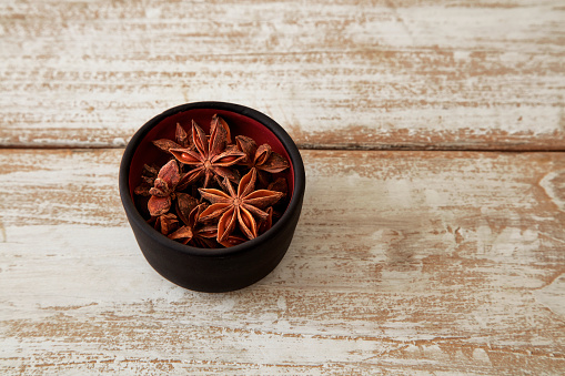 Dried star aniseed in stone bowl on wooden table.