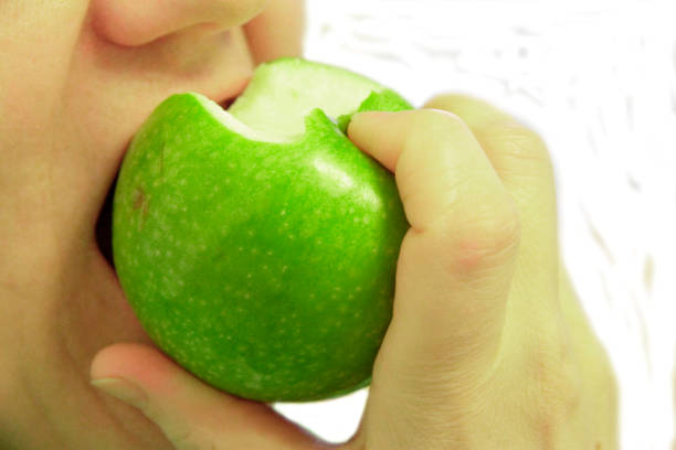 istock Woman bit a green apple isolated on the white 1227078458