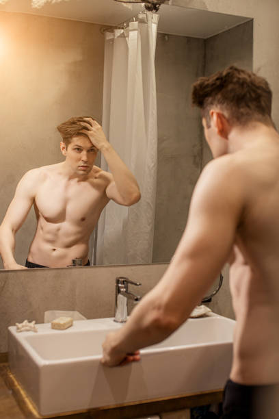 istock muscular handsome guy looking at his reflection on mirror 1227082284