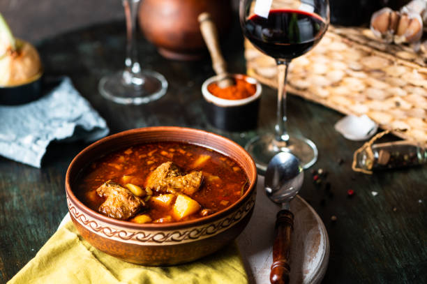 goulash ou guisado em panela de cobre com colher na mesa rústica da cozinha. eintopf, chili con carne. prato húngaro tradicional. jantar caseiro. sopa de páprica. vida morta de comida. ensopado de carne. - soup photography pan hungary - fotografias e filmes do acervo